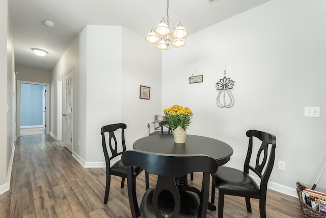 dining area with hardwood / wood-style floors and an inviting chandelier