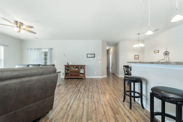 living room featuring ceiling fan with notable chandelier and hardwood / wood-style flooring