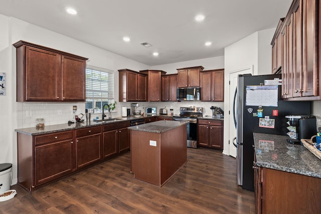 kitchen with dark stone countertops, dark hardwood / wood-style floors, a center island, and appliances with stainless steel finishes