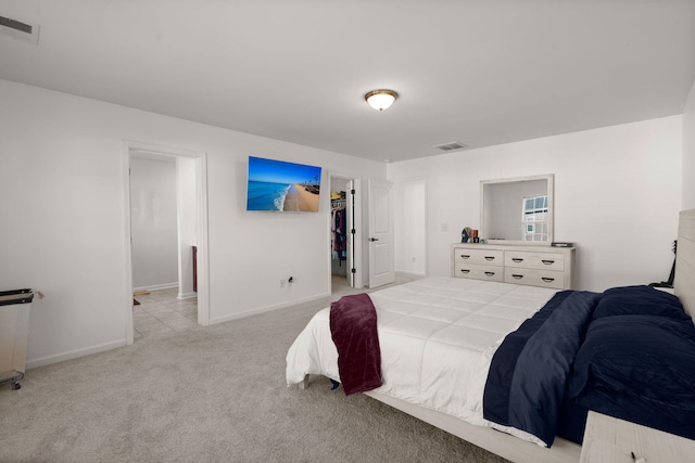 bedroom featuring light carpet and a walk in closet