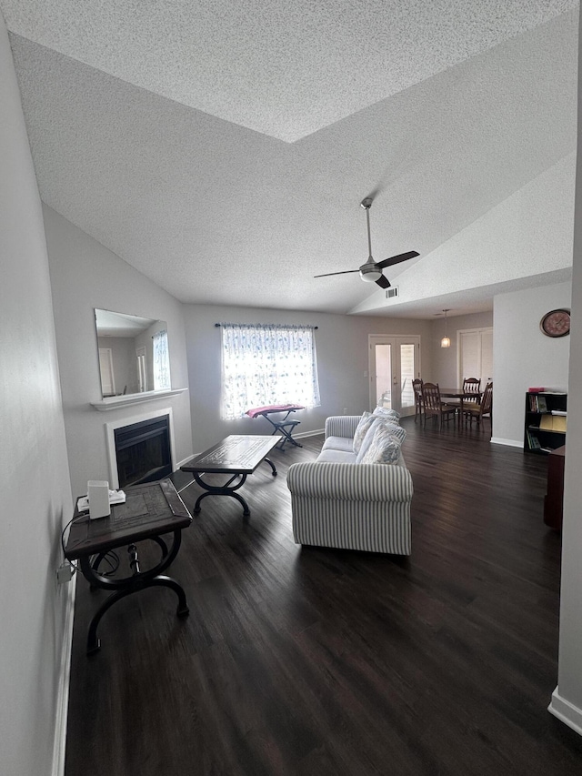 living area with a textured ceiling, a fireplace, wood finished floors, and baseboards