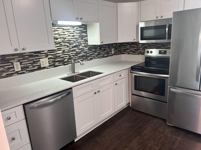 kitchen with a sink, appliances with stainless steel finishes, white cabinets, and dark wood-style flooring