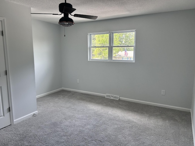 empty room featuring ceiling fan, a textured ceiling, visible vents, baseboards, and carpet