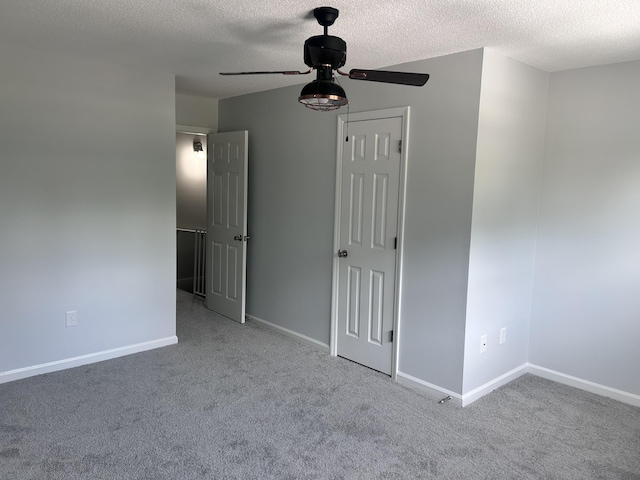 unfurnished bedroom with carpet floors, a textured ceiling, and baseboards