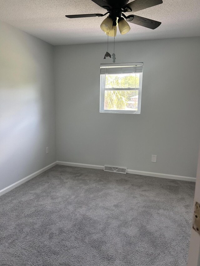 spare room featuring visible vents, carpet, a textured ceiling, and ceiling fan