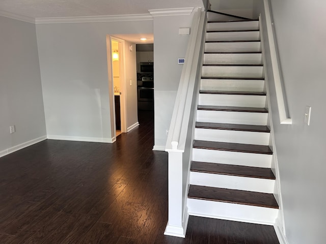 staircase featuring baseboards, ornamental molding, and wood finished floors