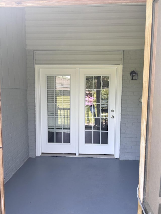 doorway to property featuring brick siding, french doors, and a patio area
