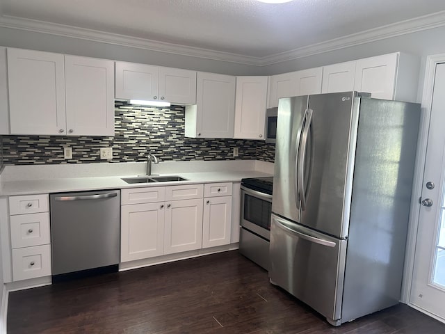 kitchen with appliances with stainless steel finishes, a sink, light countertops, white cabinetry, and ornamental molding