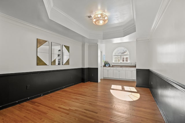 interior space featuring hardwood / wood-style flooring, a tray ceiling, and ornamental molding