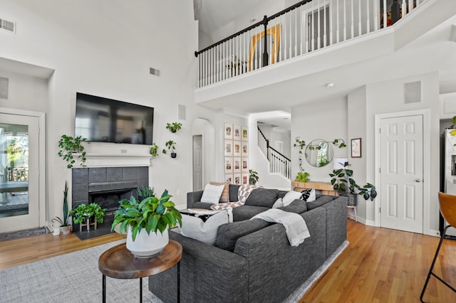 living room featuring a towering ceiling, light hardwood / wood-style floors, and a tiled fireplace