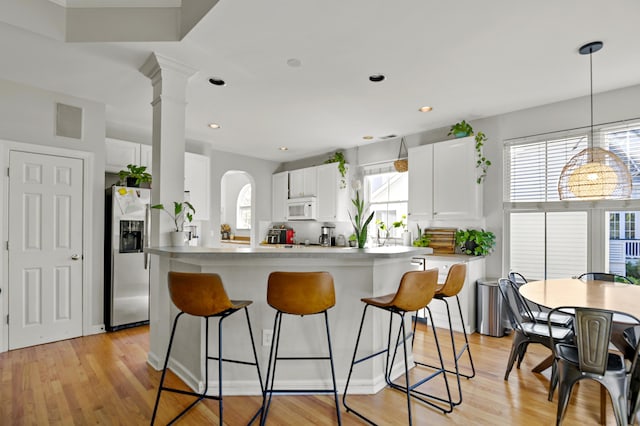 kitchen featuring light wood-type flooring, white cabinetry, a wealth of natural light, and stainless steel refrigerator with ice dispenser