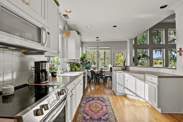 kitchen with sink, stainless steel appliances, white cabinetry, and a wealth of natural light