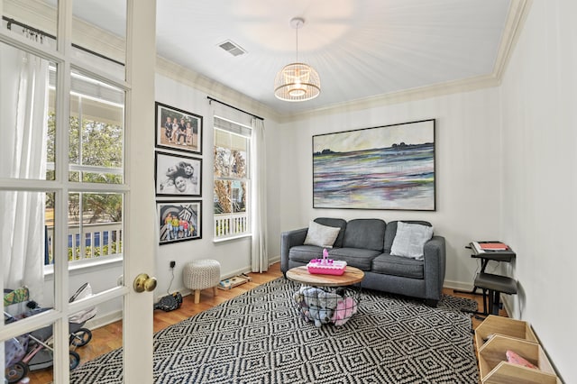 living area with wood-type flooring, ornamental molding, a healthy amount of sunlight, and french doors