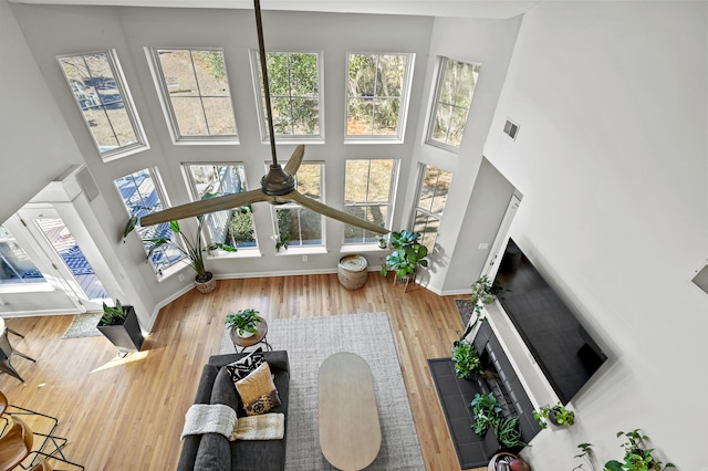 living room with hardwood / wood-style floors, a high ceiling, and ceiling fan