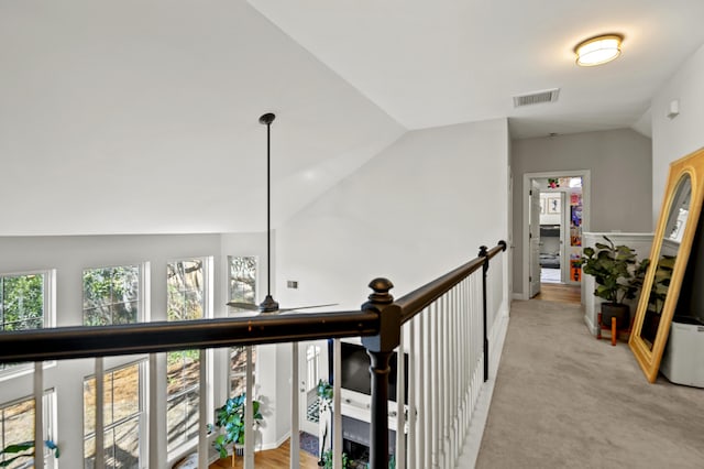 hall with vaulted ceiling, light colored carpet, and plenty of natural light