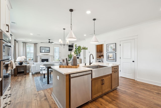 kitchen with decorative light fixtures, sink, an island with sink, stainless steel appliances, and white cabinets