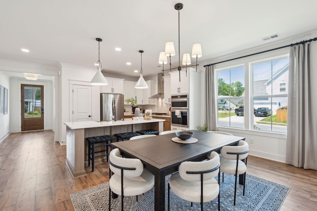 dining room featuring a notable chandelier, crown molding, and light hardwood / wood-style flooring