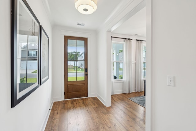 doorway featuring hardwood / wood-style flooring, ornamental molding, and a healthy amount of sunlight