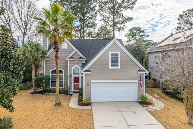 traditional-style house featuring a front yard, concrete driveway, fence, and an attached garage