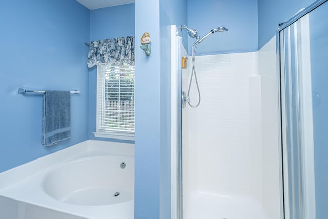 bathroom featuring a stall shower and a bath