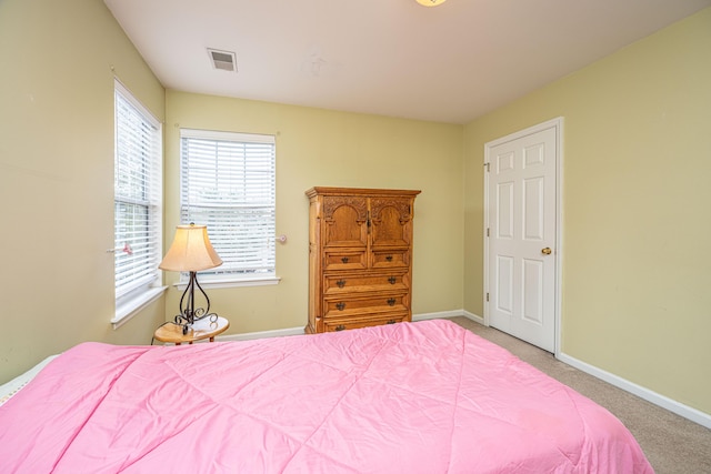 carpeted bedroom featuring multiple windows, visible vents, and baseboards