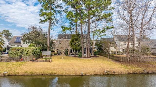 rear view of house with a water view, fence, and a yard