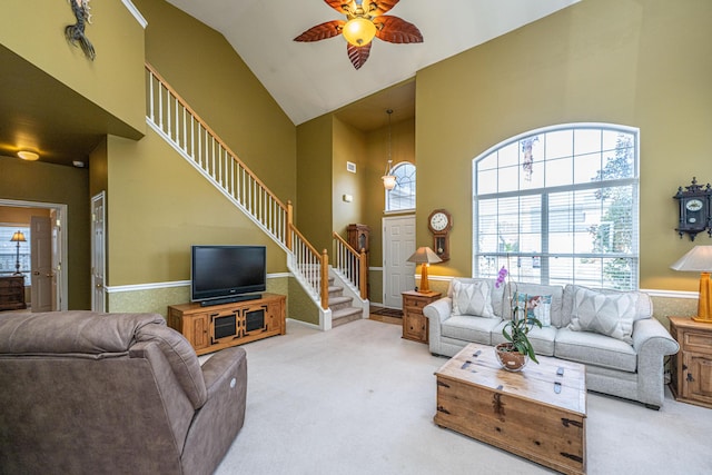 carpeted living area featuring high vaulted ceiling, stairway, and a ceiling fan