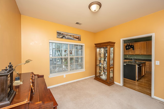 office space with baseboards, visible vents, a sink, and light colored carpet