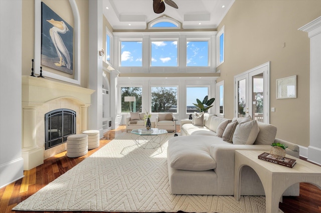 living area featuring a glass covered fireplace, a high ceiling, recessed lighting, and wood finished floors