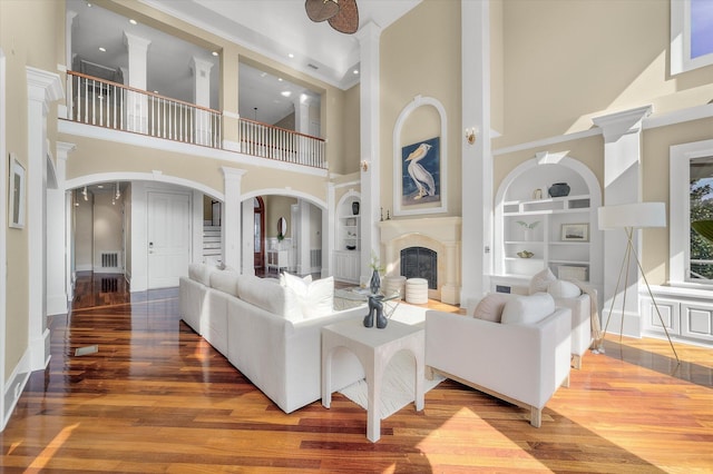 living room with visible vents, arched walkways, wood finished floors, built in shelves, and a fireplace