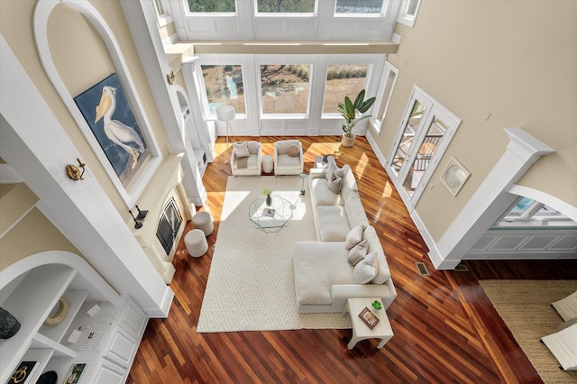 living room featuring a towering ceiling, plenty of natural light, baseboards, and wood finished floors