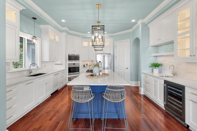 kitchen featuring stainless steel appliances, wine cooler, a sink, and white cabinets