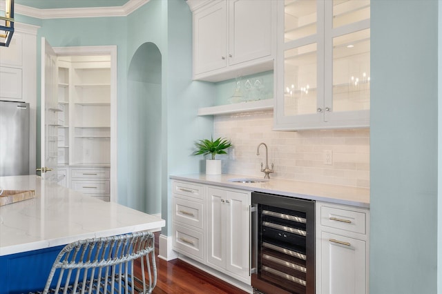 bar with beverage cooler, a sink, freestanding refrigerator, decorative backsplash, and wet bar