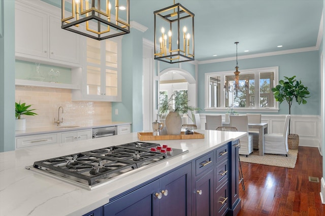 kitchen with a chandelier, stainless steel gas cooktop, a sink, white cabinets, and crown molding