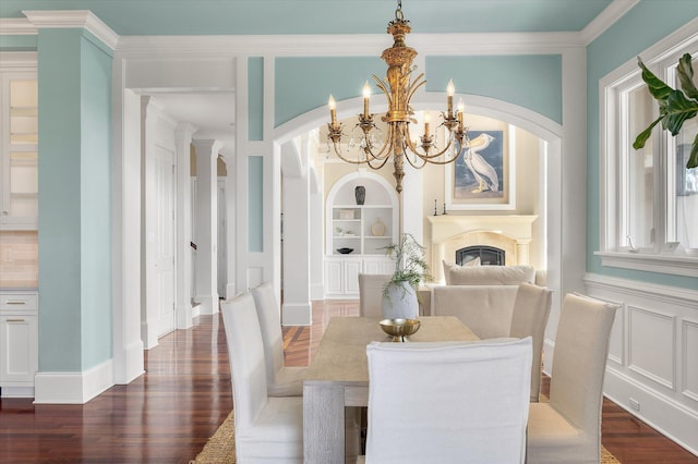 dining area featuring built in shelves, arched walkways, dark wood finished floors, a decorative wall, and a premium fireplace