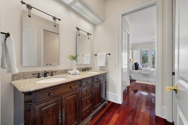 ensuite bathroom with hardwood / wood-style floors, baseboards, a sink, and ensuite bathroom