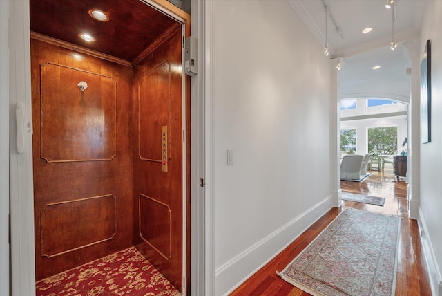 corridor with recessed lighting, wood finished floors, baseboards, elevator, and crown molding