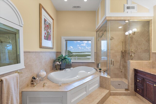 bathroom featuring a stall shower, tile walls, visible vents, and a bath