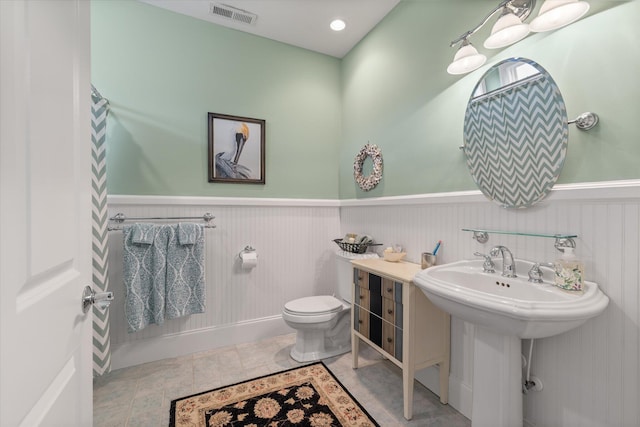 full bath featuring a wainscoted wall, visible vents, a sink, and toilet