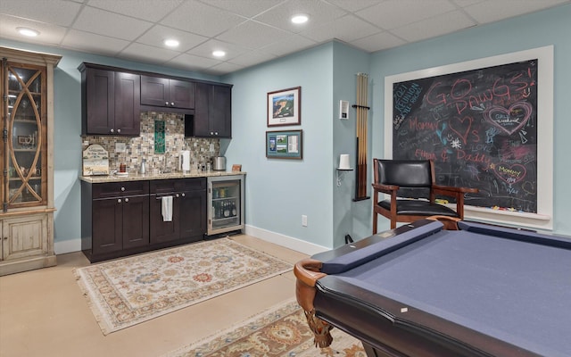 playroom featuring a paneled ceiling, recessed lighting, beverage cooler, baseboards, and indoor wet bar