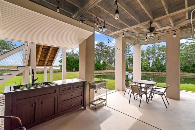 view of patio with a ceiling fan, outdoor dining space, and a water view