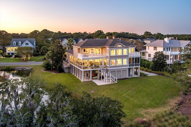 back of property at dusk featuring stairs, a lawn, and a garage