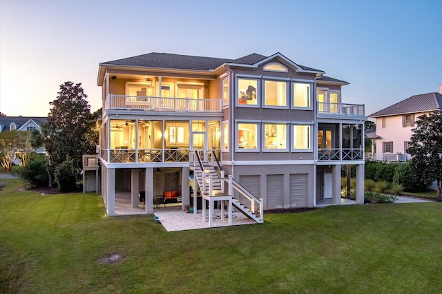 back of house with a balcony, a patio area, stairs, and a lawn