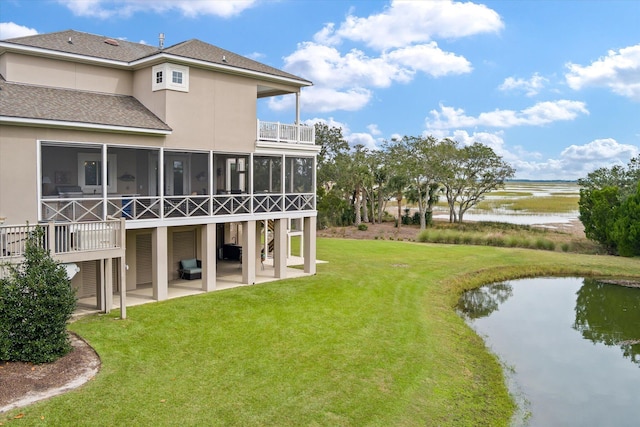 back of house with a balcony, a sunroom, a water view, a yard, and a patio area