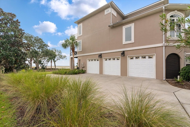 view of side of property with a garage, concrete driveway, and stucco siding