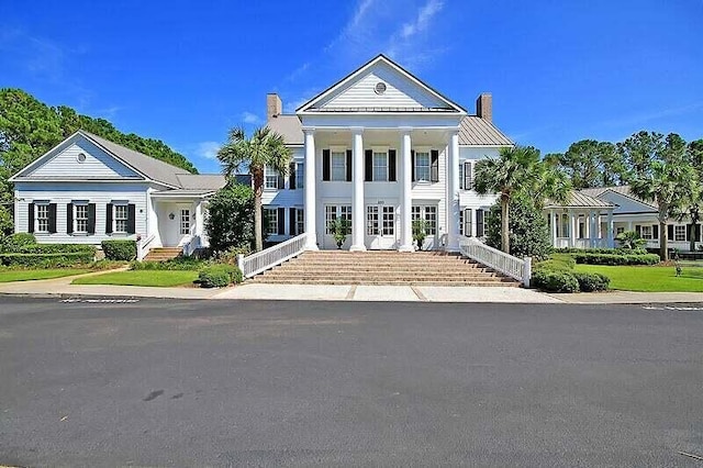 neoclassical / greek revival house featuring a chimney