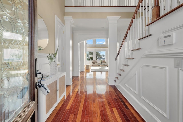 foyer entrance featuring arched walkways, french doors, dark wood-style flooring, crown molding, and stairway