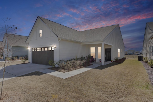 view of front of home featuring driveway, board and batten siding, a shingled roof, a garage, and central AC unit