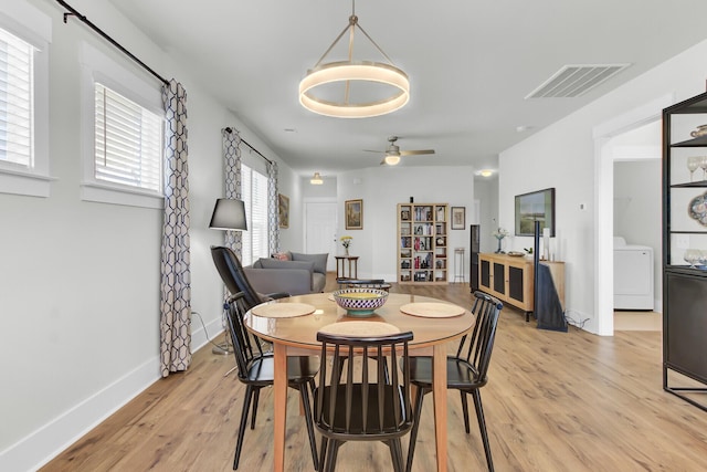 dining space with visible vents, baseboards, ceiling fan, washer / dryer, and light wood-style flooring