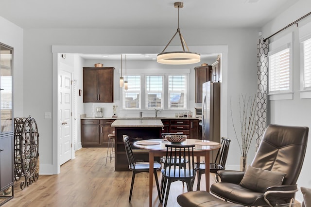 dining area featuring baseboards, a healthy amount of sunlight, and light wood-style flooring